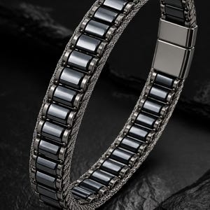 May include: A bracelet featuring a central row of polished, rectangular dark gray links flanked by two silver-toned woven mesh bands. The design includes a smooth, rectangular metal clasp closure that secures the linked structure together.