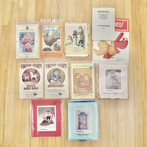 May include: A collection of 10 vintage sewing patterns for creating stuffed animals and home decor. The patterns feature a variety of designs, including a turkey, a jointed rabbit, a hobby horse, a calico mouse, a pelican, and a dollhouse. The patterns are in various colors, including red, blue, green, and brown.