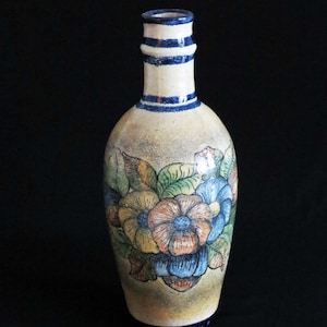 May include: A ceramic vase with a floral design. The vase is decorated with blue, yellow, orange, and green flowers. The vase has a narrow neck and a wide base.