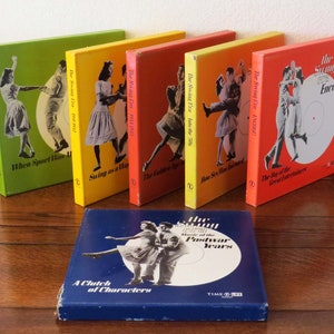 May include: A set of six vintage record albums with colorful covers featuring couples dancing. The albums are titled "The Swing Era" and each album has a different subtitle. The albums are arranged in a row on a wooden surface. A blue box with the text "The Swing Era Music of the Postwar Years" is in the foreground.