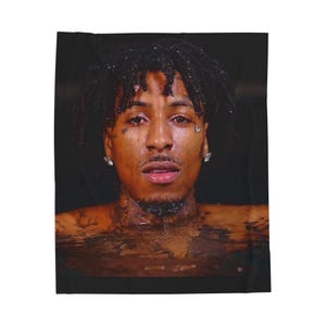 May include: A black blanket featuring a portrait of a person with dark hair and tattoos. The person is partially submerged in water, with droplets on their face. The image has a dark, moody aesthetic.