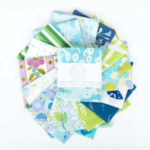May include: A collection of vintage fabric squares in various shades of blue, green, and purple, arranged in a circular pattern. The fabric pieces feature floral and geometric patterns. A label reads "Vintage Sheets 14 Fat Quarter Bundles Kelly's Custom Colors 14" x 22".