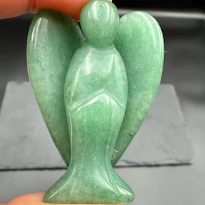 May include: A green aventurine angel figurine with outstretched wings. The angel is carved from a single piece of stone and has a smooth, polished finish. The figurine is approximately 3 inches tall.