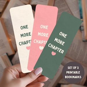 Puede incluir: Un conjunto de tres marcapáginas rectangulares en color crema, rosa y verde oscuro. Cada marcapáginas presenta el texto ONE MORE CHAPTER en una fuente sans-serif en negrita, acompañado de un pequeño icono de corazón y esquinas redondeadas.