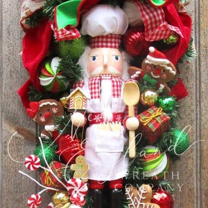 May include: A festive Christmas decoration featuring a chef nutcracker doll, gingerbread men, and candy canes. The design incorporates red, green, and white ribbons, ornaments, and gift boxes, creating a holiday theme.