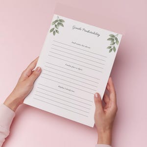 May include: A white journal with the title "Gentle Predictability" and lined pages is held against a pink background. The journal has green leaf illustrations and prompts for self-reflection, including "Small routines that calm me:" and "Familiar places or objects:"