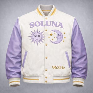 Puede incluir: Chaqueta universitaria blanca con mangas y detalles en lavanda. La chaqueta presenta la palabra "SOLUNA" sobre un diseño bordado de sol y luna. El número "963 Hz" está bordado debajo. El cuello y los puños tienen rayas amarillas y blancas.