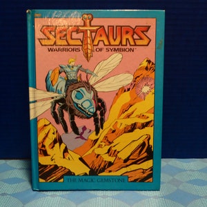 May include: A vintage "Sectaurs: Warriors of Symbion" comic book. The cover features a warrior riding a large insect-like creature over a rocky landscape. The title is in yellow and orange, with the words "The Magic Gemstone" at the bottom.