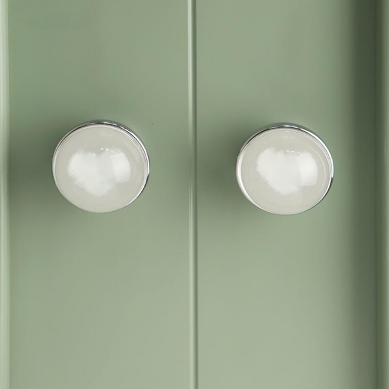 May include: A white ceramic mug with a black handle and the text "But First, Coffee" in a bold, black font. The mug is filled with a dark liquid, likely coffee, and sits on a light-colored surface.