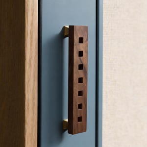 Pode incluir: Uma caneca de cerâmica branca com uma alça preta e o texto "But First, Coffee" em negrito preto. A caneca está sobre um fundo desfocado, sugerindo um ambiente acolhedor.