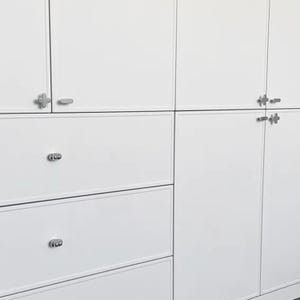 May include: White cabinets and drawers with silver-colored hardware. The cabinets have a clean, modern design with a smooth, glossy finish. The drawers have round, decorative pulls.