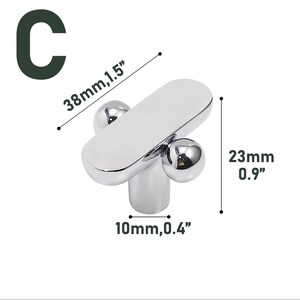 May include: A chrome-finished cabinet knob with a rounded rectangular top and two spherical accents. The knob measures 1.5 inches long, 0.9 inches high, and 0.4 inches wide. The letter "C" is in the upper left corner.