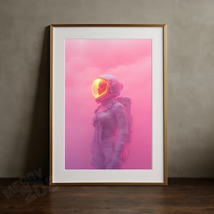 Könnte beinhalten: Gerahmter Kunstdruck mit einem Astronauten in einem weißen Raumanzug und Helm mit leuchtend gelbem Visier. Der Hintergrund ist ein Farbverlauf aus Rosa und Lila, der eine surreale Atmosphäre erzeugt. Der Astronaut steht in einer nachdenklichen Pose.