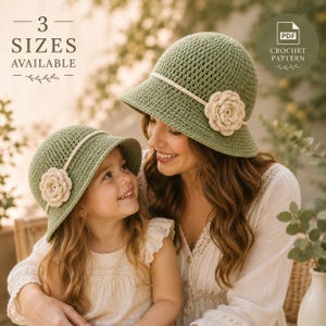 May include: Two matching sage green crochet bucket hats with a cream-colored band and a cream-colored crocheted flower accent on the side. The image includes text stating 3 SIZES AVAILABLE and PDF CROCHET PATTERN.