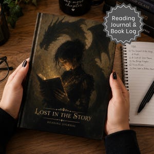 May include: A hardback reading journal titled Lost in the Story featuring a dark illustration of a person reading a glowing book with a large dragon silhouette behind them. The cover has gold text and the journal is held open on a wooden surface.