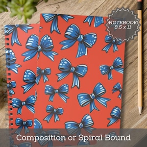 May include: Two spiral-bound notebooks with a red cover featuring a pattern of blue bows. The notebooks are labeled "NOTEBOOK 8.5 x 11" and "Composition or Spiral Bound". A pencil rests on the wooden surface.