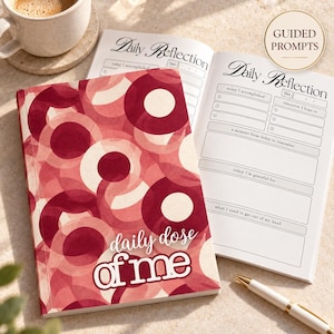 May include: A journal with a red and pink overlapping circle pattern on the cover and the text daily dose of me. The open pages feature the heading Daily Reflection with sections for today I accomplished, tomorrow I hope to, a moment from today to remember, today I'm grateful for, and what I need to get out of my head.