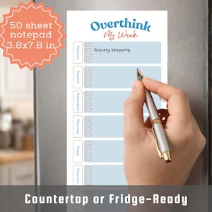May include: A notepad with the words "Overthink My Week" in blue and orange. The notepad is 3.8 x 7.8 inches and has a weekly schedule with space for notes. A hand is holding a pen, writing on the notepad. The notepad is labeled "Countertop or Fridge-Ready."