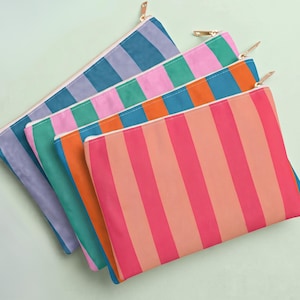 May include: A set of four rectangular zippered pouches arranged in a fan pattern. Each pouch features vertical stripes in distinct color combinations, including lavender and blue, pink and green, orange and blue, and coral and bright pink with gold zippers.