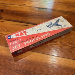 May include: Vintage Ray Jet Propulsion model airplane box. The box is red and white with the text "World's First Model Airplane to Fly By Jet Propulsion Rocket". The box features a drawing of a jet airplane.