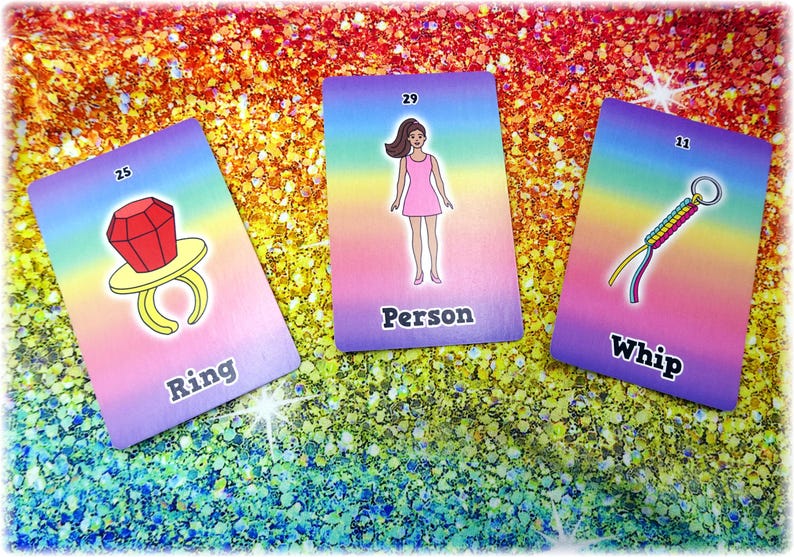 May include: Three colorful cards with illustrations and text. One card shows a ring with a large red gem and the word "Ring". Another card depicts a person in a pink dress with the word "Person". The third card shows a whip with the word "Whip".