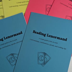 May include: A stack of colorful guidebooks titled "Reading Lenormand" in pink, blue, and yellow. Each book features the title, a subtitle, and a graphic of two cards. The Rainbow Willard Studio website is listed on the blue book.