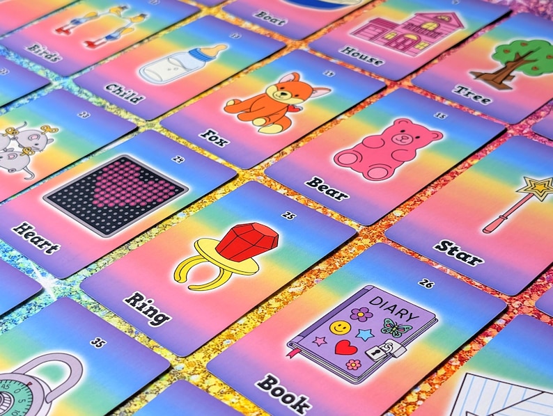 May include: A collection of colorful flashcards with various illustrations and words. The cards feature images of a fox, bear, ring, and diary, among others. The background has a rainbow gradient.