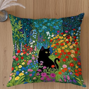 May include: Square cushion featuring a black cat with yellow eyes, set in a vibrant garden of colourful flowers. The cushion has a teal background and is placed on a wooden surface.