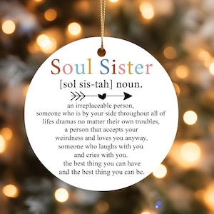 Puede incluir: Adorno redondo blanco con el texto "Soul Sister" en letras coloridas. El adorno incluye una definición de "Soul Sister" y está suspendido por un hilo dorado, perfecto para regalar.