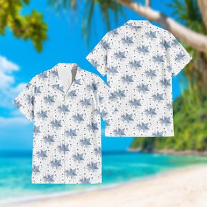 May include: White button-down shirt with a pattern of blue stars and smaller dark blue stars. The shirt has short sleeves and a relaxed fit, suitable for casual wear. The design is repeated on the back of the shirt.