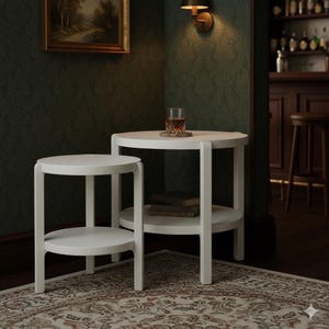 Puede incluir: Dos mesas auxiliares redondas blancas con un estante inferior. Una mesa tiene un vaso de líquido ámbar encima. Las mesas están en una habitación con una alfombra estampada y paredes verde oscuro. Las mesas tienen aproximadamente 50 cm de diámetro.