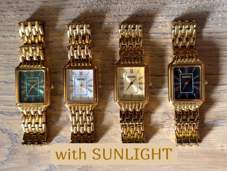 Pu&ograve; includere: Quattro orologi da polso Seiko con casse rettangolari color oro e cinturini a maglie color oro abbinati. I quadranti presentano numeri romani e la scritta "SEIKO". I quadranti sono verde, bianco, oro e nero. Il testo recita "with SUNLIGHT".