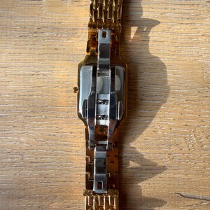 Pu&ograve; includere: Un orologio da polso in metallo color oro con cassa rettangolare e bracciale a maglie multiple. Il retro della cassa &egrave; color argento e il bracciale include una chiusura a farfalla in acciaio inossidabile color argento.