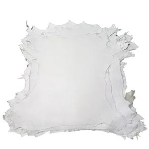 Pode incluir: Uma pilha de peles de couro brancas com bordas irregulares e irregulares. As peles são sobrepostas, revelando a textura e a forma natural do material. A cor é um branco suave, sugerindo um processo de curtimento natural.