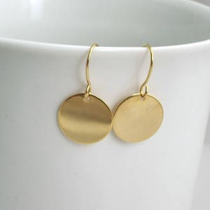 May include: A pair of gold-toned disc earrings with a simple, minimalist design.
