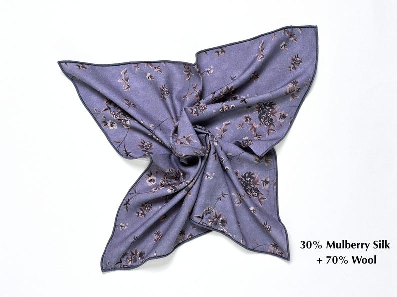 May include: A lavender scarf with a floral pattern in shades of brown and gray. The scarf is made of 30% mulberry silk and 70% wool. The edges are finished with a dark gray border. The scarf is displayed on a white background.