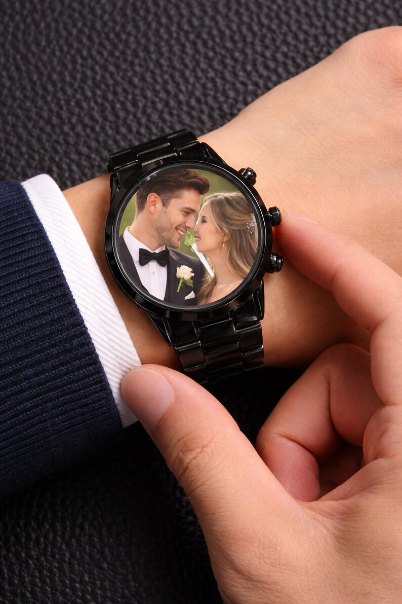 Peut inclure: Montre-bracelet noire avec une photo d'un couple sur le cadran. La montre a un bracelet en m&eacute;tal noir et un cadran rond. Le couple sur la photo sourit, peut-&ecirc;tre lors d'un mariage. La montre est port&eacute;e au poignet.
