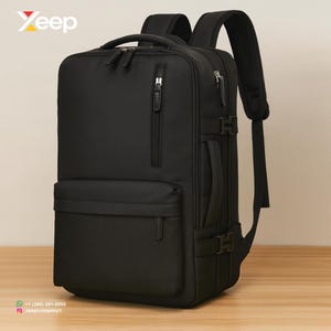 Peut inclure: Sac à dos noir avec plusieurs compartiments, fermetures éclair et bretelles réglables. Il comporte une poignée supérieure et une poche avant. La marque "Yeep" est visible en haut à gauche. Le sac à dos est sur une surface en bois.