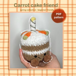 Peut inclure: Peluche en forme de gâteau aux carottes crocheté, avec une bougie. Le gâteau présente des sections marron, blanches et orange, avec de petits pieds marron. Le texte sur l'image indique "Carrot cake friend", "spring collection - beginner friendly", et "PDF pattern".