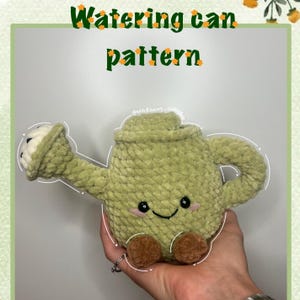 May include: A soft, light green watering can toy with a smiling face, brown feet, and a white spout. The image includes the text "Watering can pattern".
