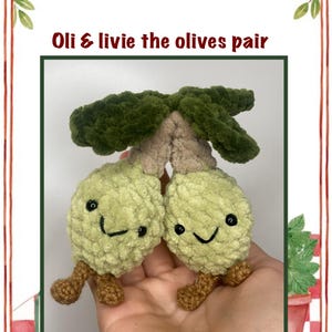 May include: A pair of crocheted olive plushies with smiling faces and brown feet. The olives have green leaves and are labeled "Oli & Livie the olives pair". The background features a red and white checkered pattern with pizza and wine.