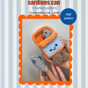 May include: A crocheted sardine can with two grey fish. The can is orange and blue with a smiling face. The text "sardines can" and "Crochet pattern" are visible. The pattern is for an intermediate level and is a PDF.
