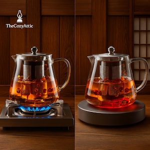 Op de afbeelding: Twee glazen theepotten met roestvrijstalen infusers, gevuld met een roodbruine vloeistof en bessen. Eén theepot staat op een gasfornuis met een blauwe vlam, de andere op een zilveren voet. Het Cozy Attic-logo staat linksboven.