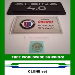 May include: A set of Alpina car emblems and stickers. The top emblem is black with the word "ALPINA" and the number "4.8" in silver. Below is a sticker with the Alpina logo and "Castrol Formula SLX 0w-30" text. A small sticker with the Alpina logo is also visible. The text "CLONE set" is at the bottom.
