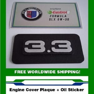 May include: An engine cover plaque and oil sticker set. The plaque is black with the number "3.3" in silver. The oil sticker features the Castrol Formula SLX 0W-30 logo and the Alpina logo.