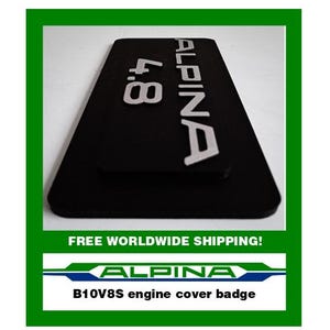 May include: Black engine cover badge with the word "ALPINA" in silver lettering. The badge also features the numbers "4.8" in silver. The text "B10V8S engine cover badge" is below the ALPINA logo.