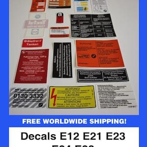 May include: A selection of automotive decals, including warning labels and informational stickers. The decals feature text in multiple languages and are designed for BMW E12, E21, E23, E24, and E28 models. The image is set against a blue background.