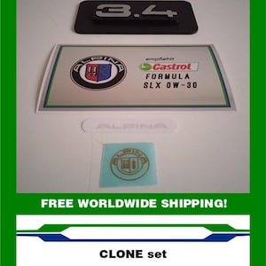May include: A set of Alpina car emblems and decals. The image includes a black emblem with the number "3.4", a rectangular sticker with the Alpina logo and "Castrol Formula SLX 0W-30" text, and a small blue sticker with the Alpina logo. The text "CLONE set" is also present.