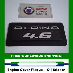 May include: Black engine cover plaque with the word "ALPINA" and the number "4.6" in silver lettering. Includes a Castrol oil sticker and an Alpina logo. The image is framed in green.