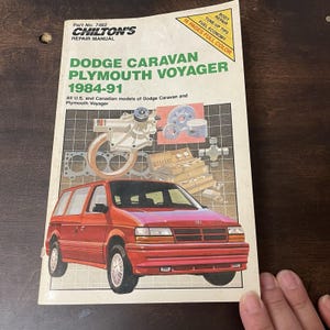 May include: A Chilton's repair manual for 1984-91 Dodge Caravan and Plymouth Voyager models. The cover features a red minivan illustration, technical diagrams of engine parts, and text including Part No. 7482 and 16 pages full color.
